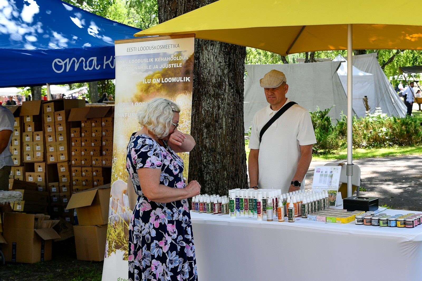 Woman browsing products at an outdoor market stall.