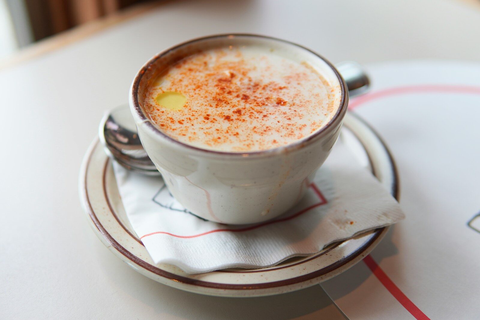 A cup of creamy soup with paprika and butter.